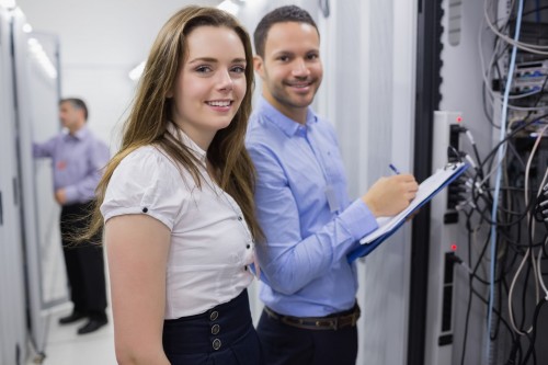 Two smiling  technicians checking the servers in data center